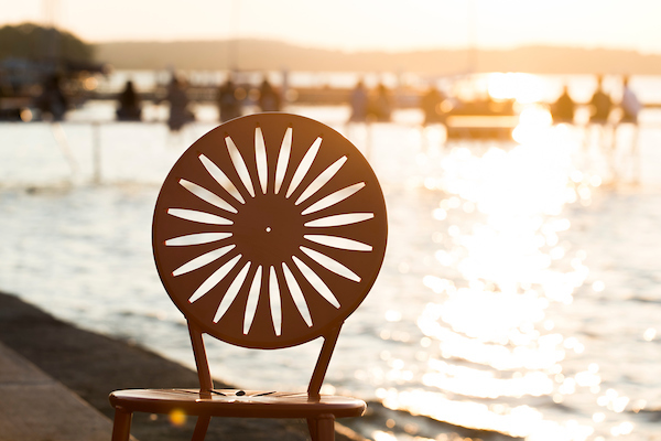 Photo of a Memorial Union Terrace chair with the sun setting over Lake Mendota in the background.