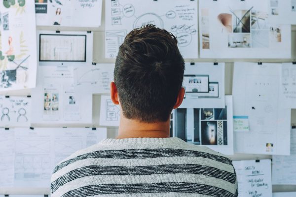 A person looking at a wall full of thumbnail ideas, sketches, photos and diagrams.