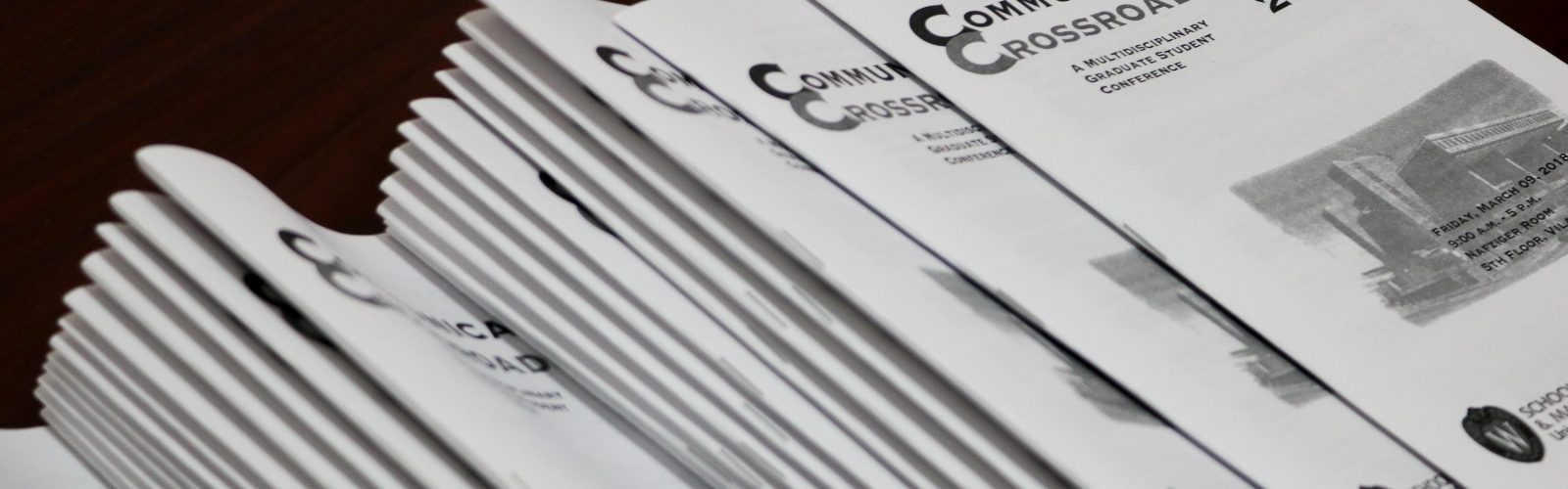 A stack of programs from the Communications Crossroads conference 2018.