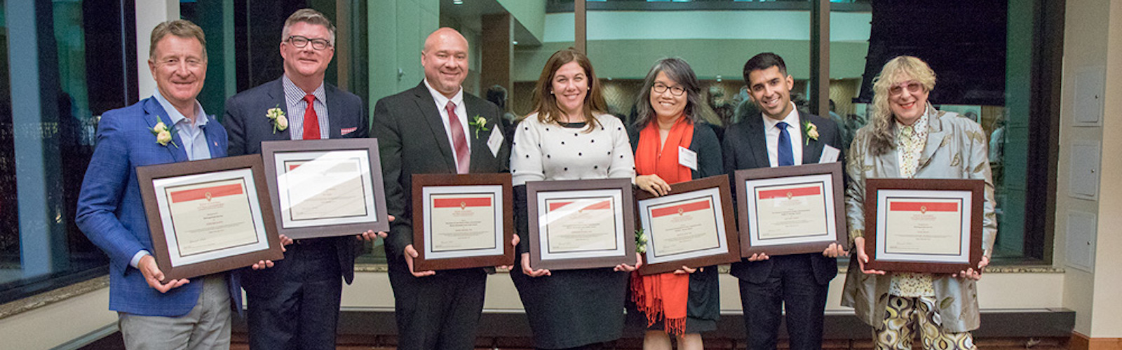 Seven 2019 SJMC Alumni Award Winners pose with their plaques