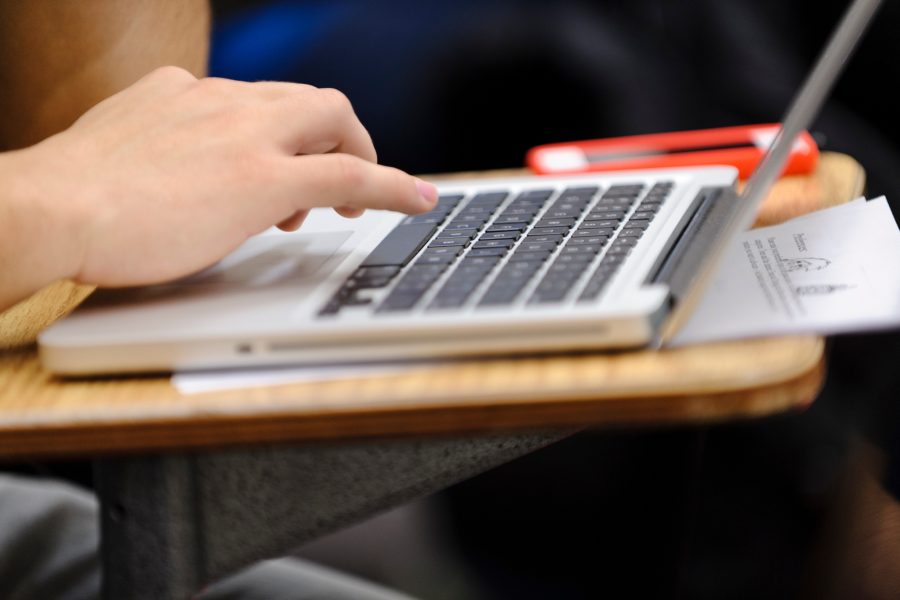 A student takes notes on a laptop computer.