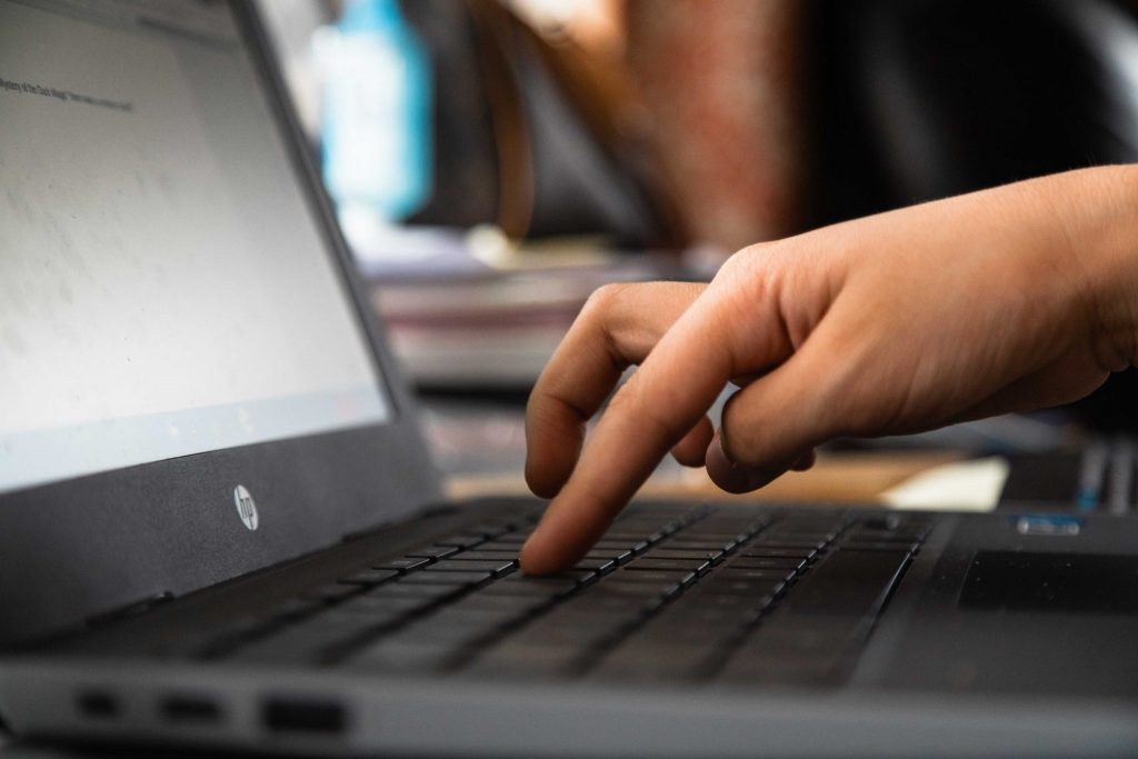 A close up of a laptop keyboard, with a child's finger lined up to press a key.