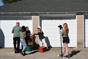 Students grind corn cobs using a hand crank