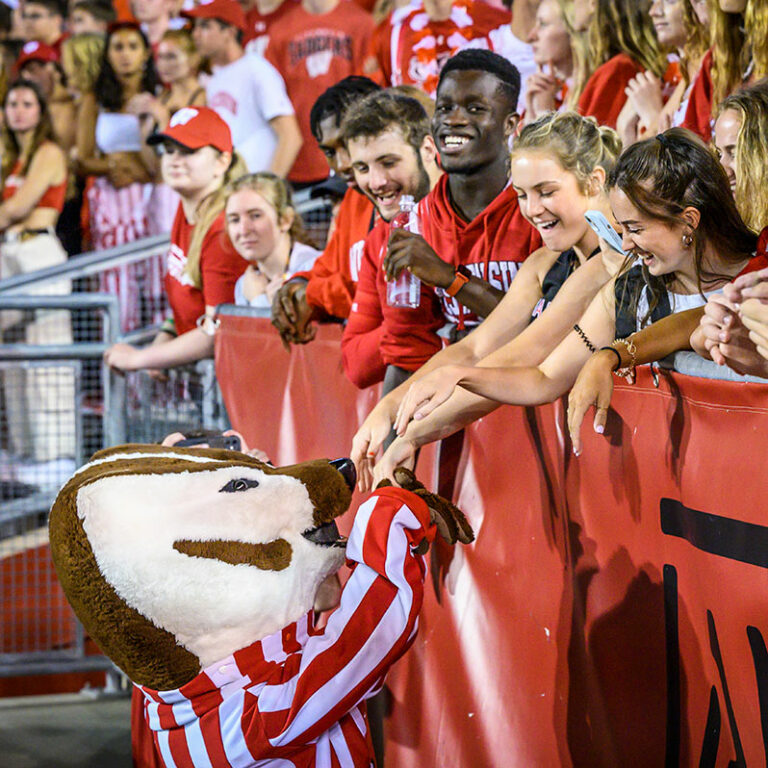 Bucky Badger high fives students at a UW-Madison football game