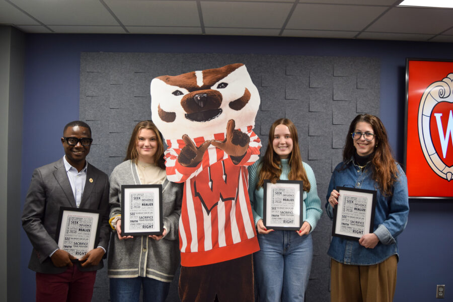 Graduating professional masters students pose with a cutout of Bucky Badger.