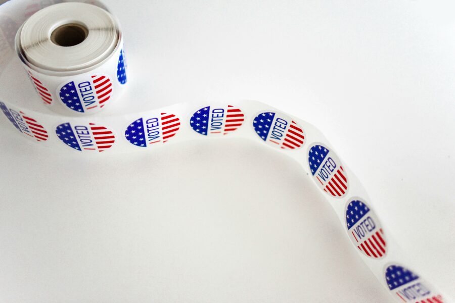 A strip of "I Voted" stickers unrolling from a large roll of stickers