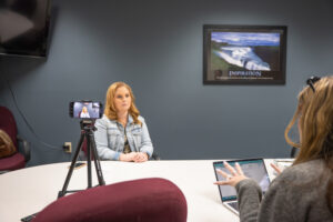 Foster mom Mandy Boge sits at a table in a conference room while being interviewed by one of the students in J445 Creative Campaign Messages.