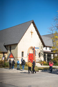 Students in J445 Creative Campaign Messages cross the street in Sheboygan by a church.