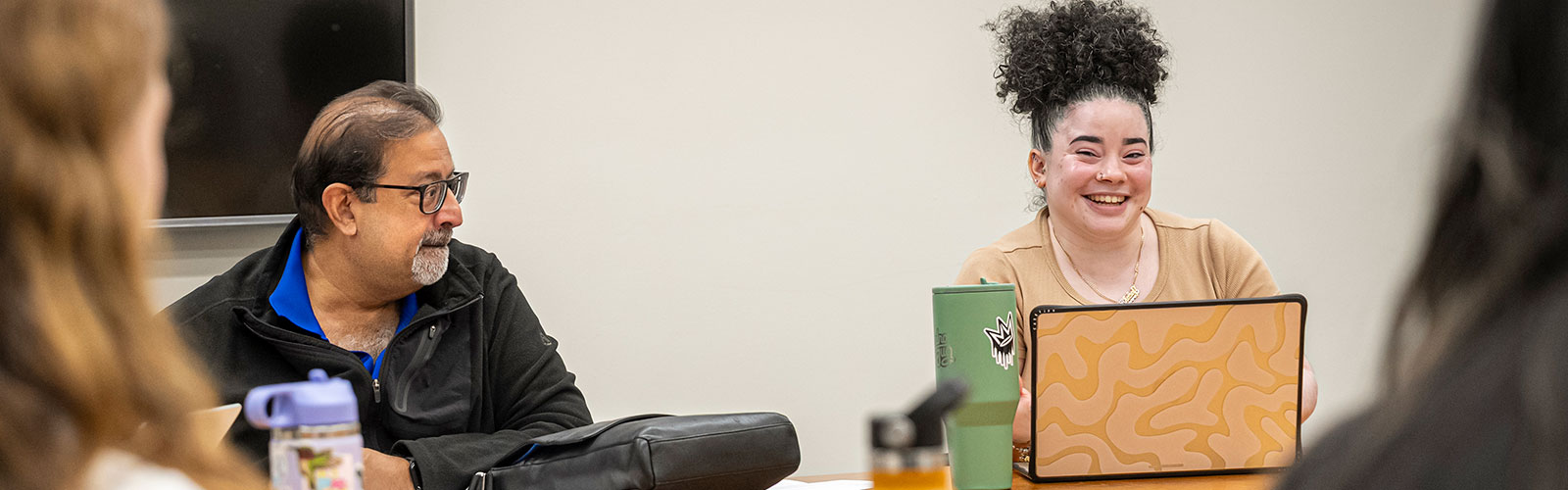 A female graduate student laughs during a mass communication research meeting