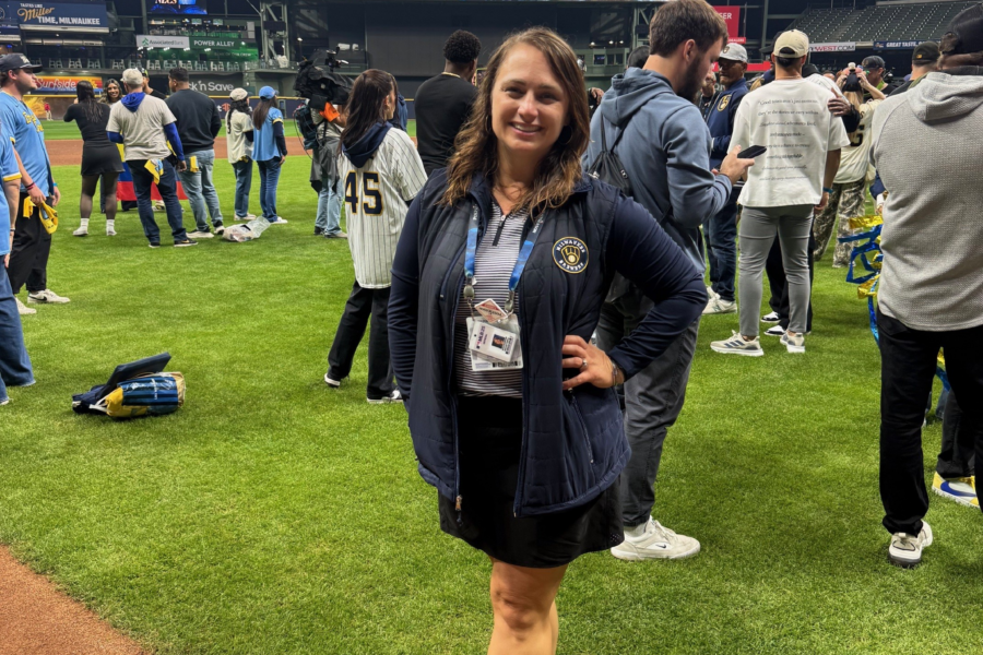 A woman poses on a baseball field with a screen behind her that reads "NLCS Bound"