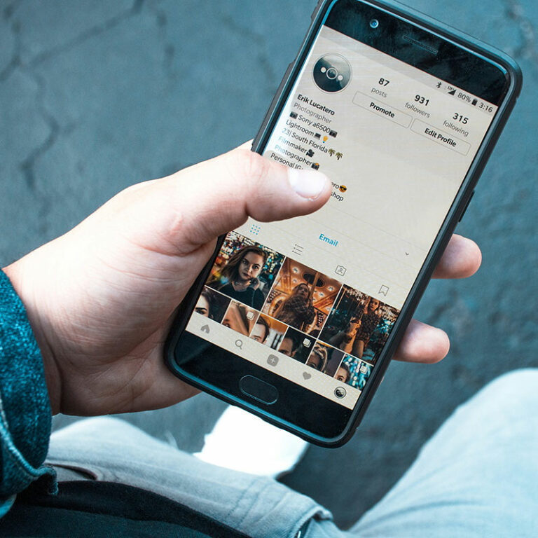 A hand holds a smart phone with an Instagram account on the screen.