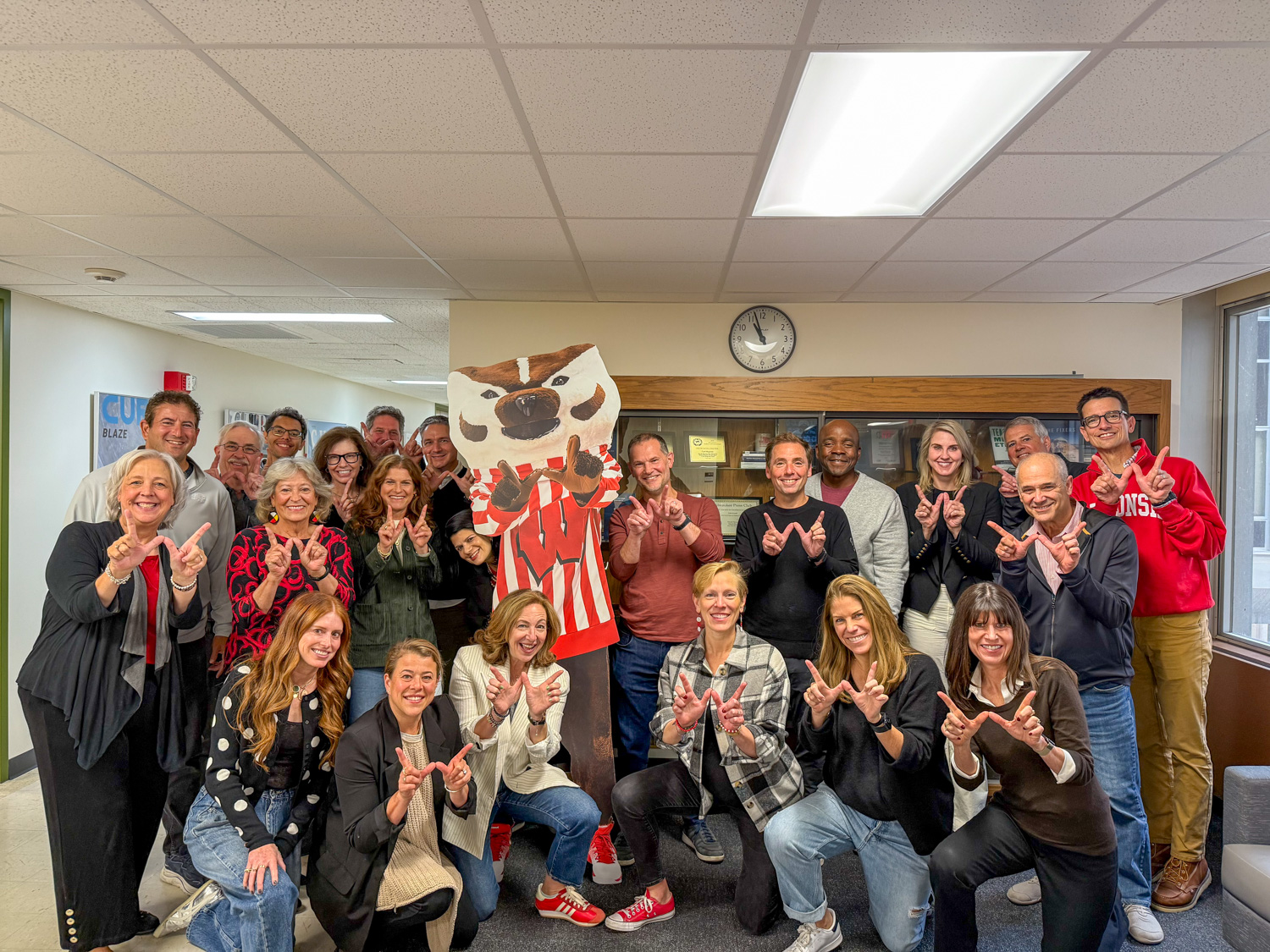 A group of alumni pose together with a cardboard cutout of Bucky Badger.