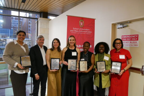 A group of six women and one man pose together with awards from the School of Journalism and Mass Communication