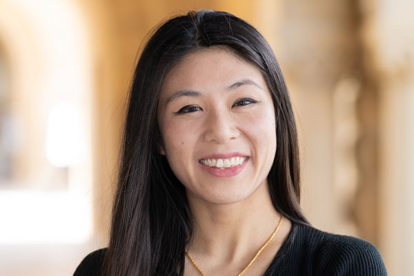 A woman with black hair wearing a black shirt smiles while outdoors